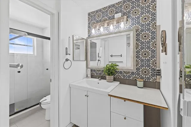 a bathroom with a granite countertop sink a toilet and shower