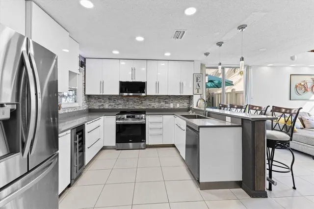 a large kitchen with stainless steel appliances granite countertop a stove top oven a sink a dining table and chairs