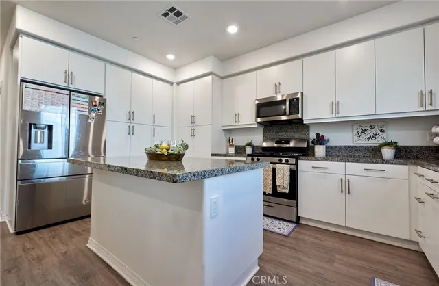 a kitchen with stainless steel appliances granite countertop a stove a sink and a refrigerator