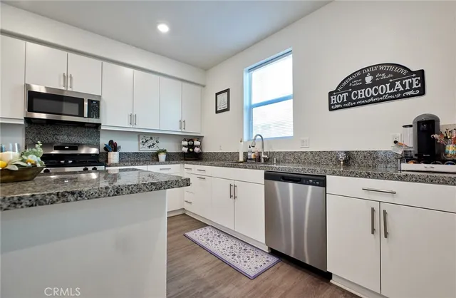 a kitchen with granite countertop stainless steel appliances a sink a stove and cabinets