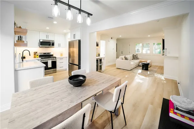 a kitchen with stainless steel appliances a dining table chairs refrigerator and stove