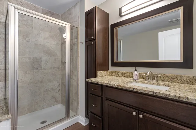 a bathroom with a granite countertop sink a mirror and a shower