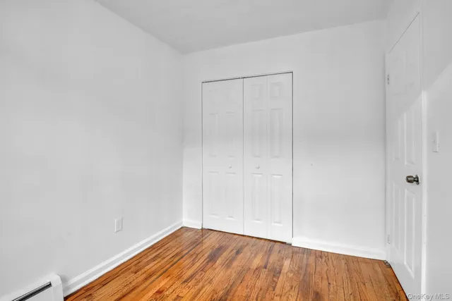 a view of an empty room with wooden floor and closet