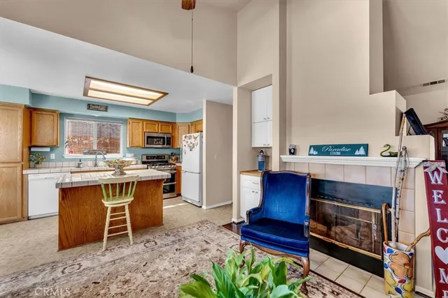 a living room with stainless steel appliances kitchen island granite countertop furniture and a fireplace