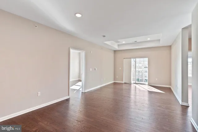 a view of an empty room with wooden floor and windows