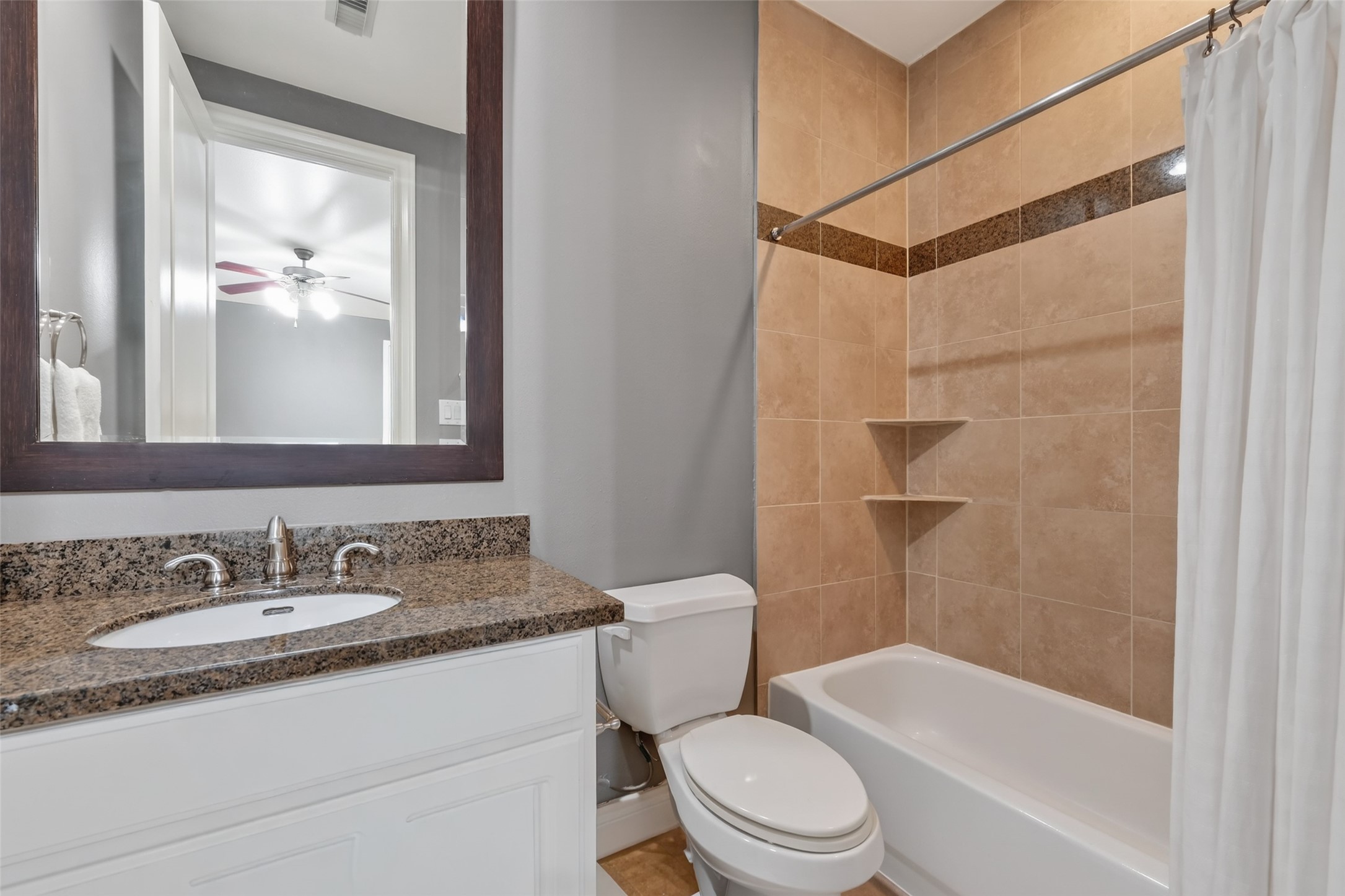 620 Rutland Street, Unit A Houston, TX 77007 - Photo 11 of 46 This bathroom features a modern design with a granite countertop, an undermount sink, and a large mirror. It includes a tiled shower-tub combo with built-in shelving and a neutral color palette.