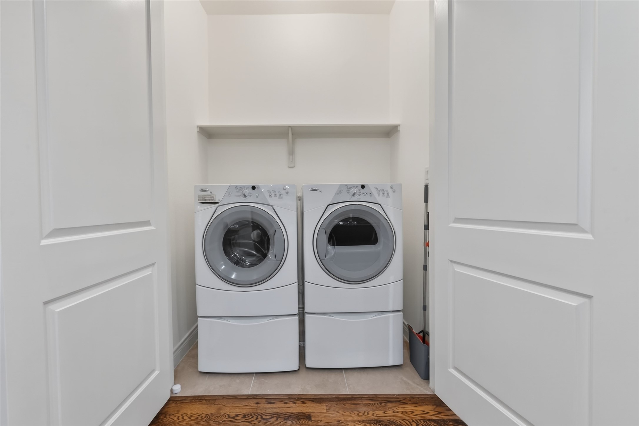620 Rutland Street, Unit A Houston, TX 77007 - Photo 20 of 46 This photo shows a compact laundry closet with a front-loading washer and dryer, neatly tucked behind double doors, featuring a shelf above for storage.