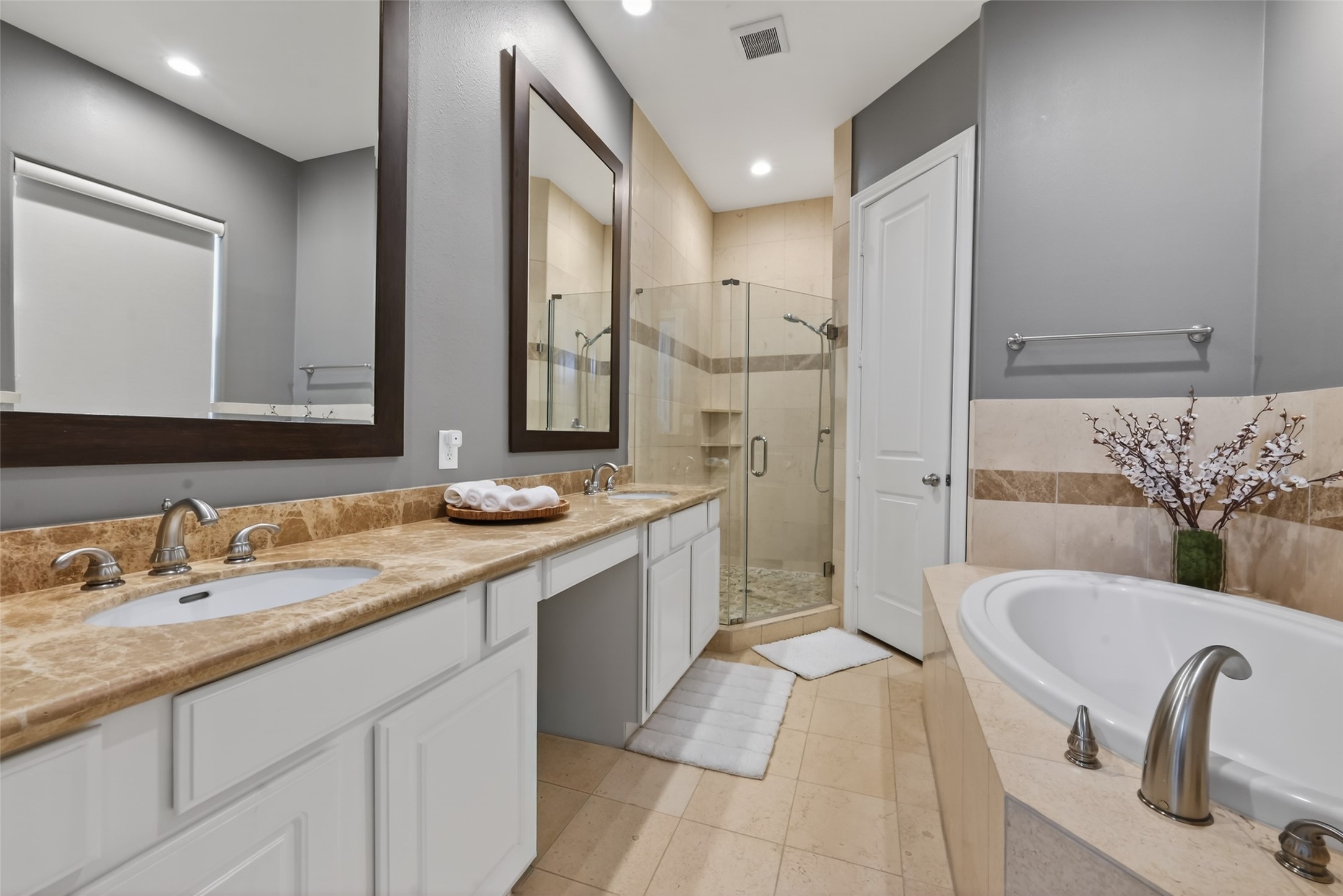 620 Rutland Street, Unit A Houston, TX 77007 - Photo 25 of 46 This bathroom features a sleek design with dual sinks on a marble countertop, a glass-enclosed shower, and a spacious bathtub. The neutral tones and modern fixtures create a serene and inviting atmosphere.