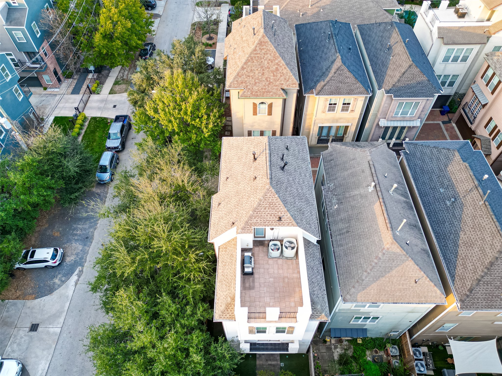 620 Rutland Street, Unit A Houston, TX 77007 - Photo 34 of 46 This aerial view showcases a row of modern townhouses with distinct, varied roof designs. The neighborhood features tree-lined streets and neatly parked cars, suggesting a peaceful, urban residential area.