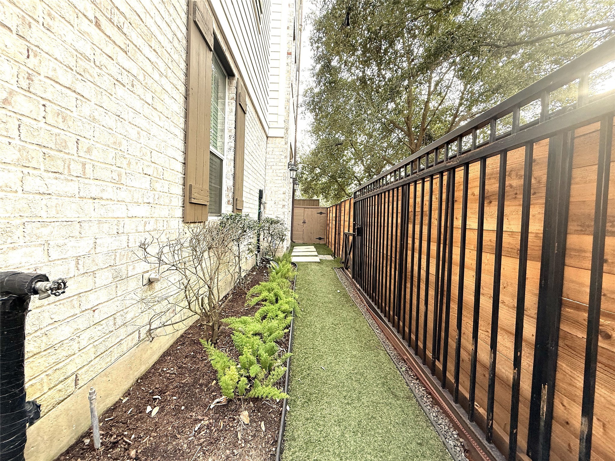 620 Rutland Street, Unit A Houston, TX 77007 - Photo 5 of 46 The side yard with a pathway to the main door of the property. The area is lined with low-maintenance landscaping, including small shrubs and a wooden fence, providing a private, cozy outdoor space.