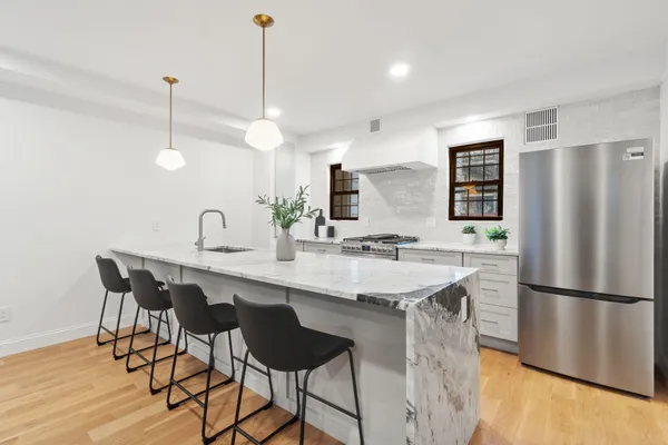 a kitchen with a sink a refrigerator and chairs