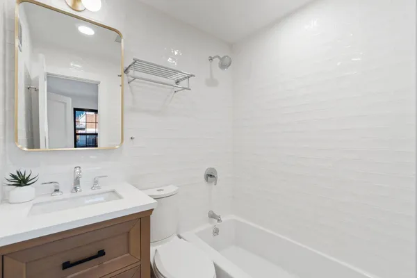 a bathroom with a granite countertop sink a toilet and shower