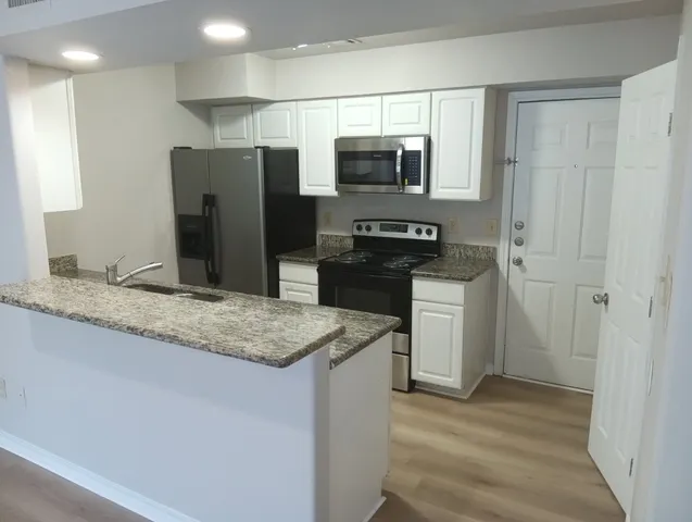 a kitchen with stainless steel appliances granite countertop a refrigerator and a sink