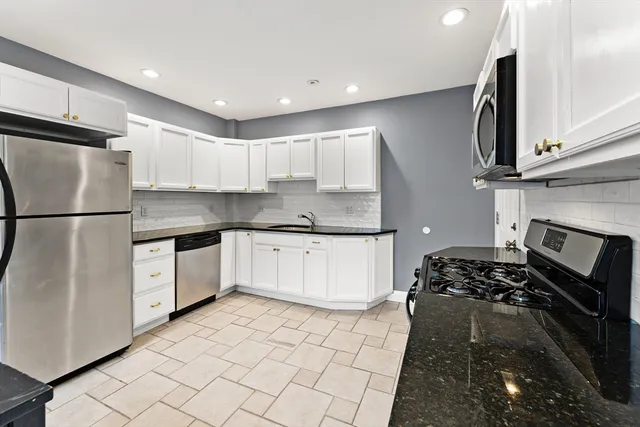 a kitchen with stainless steel appliances granite countertop a stove a sink and a refrigerator