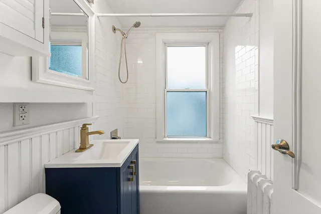 a bathroom with a sink vanity mirror and tub