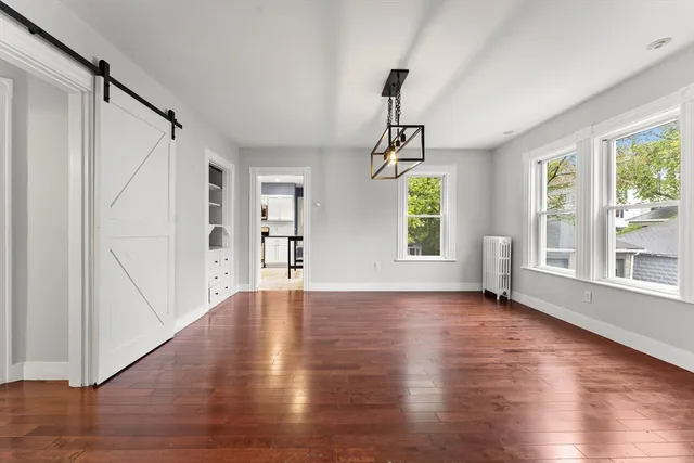 a view of an empty room with window and wooden floor