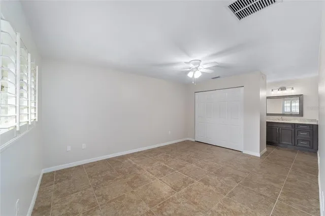 an empty room with a chandelier fan and windows