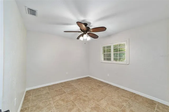 an empty room with a window and a ceiling fan