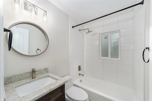 a bathroom with a granite countertop sink mirror vanity and toilet