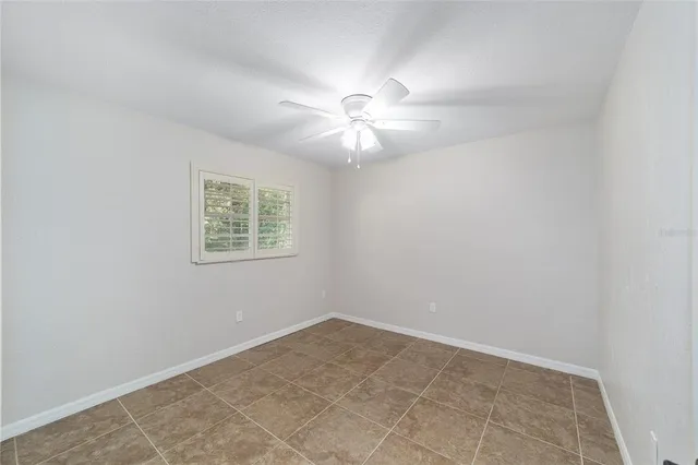 an empty room with a window and a fan