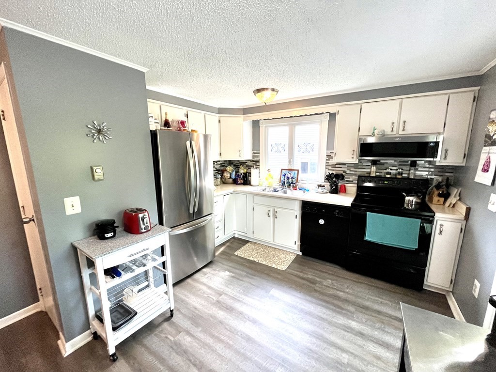 270 Sunderland Road, Unit 95 Worcester, MA 01604 - Photo 11 of 17 a kitchen with stainless steel appliances kitchen island granite countertop a refrigerator a sink dishwasher a stove top oven and a dining table with wooden floor
