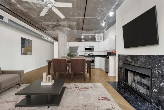a living room with stainless steel appliances furniture a fireplace and a flat screen tv