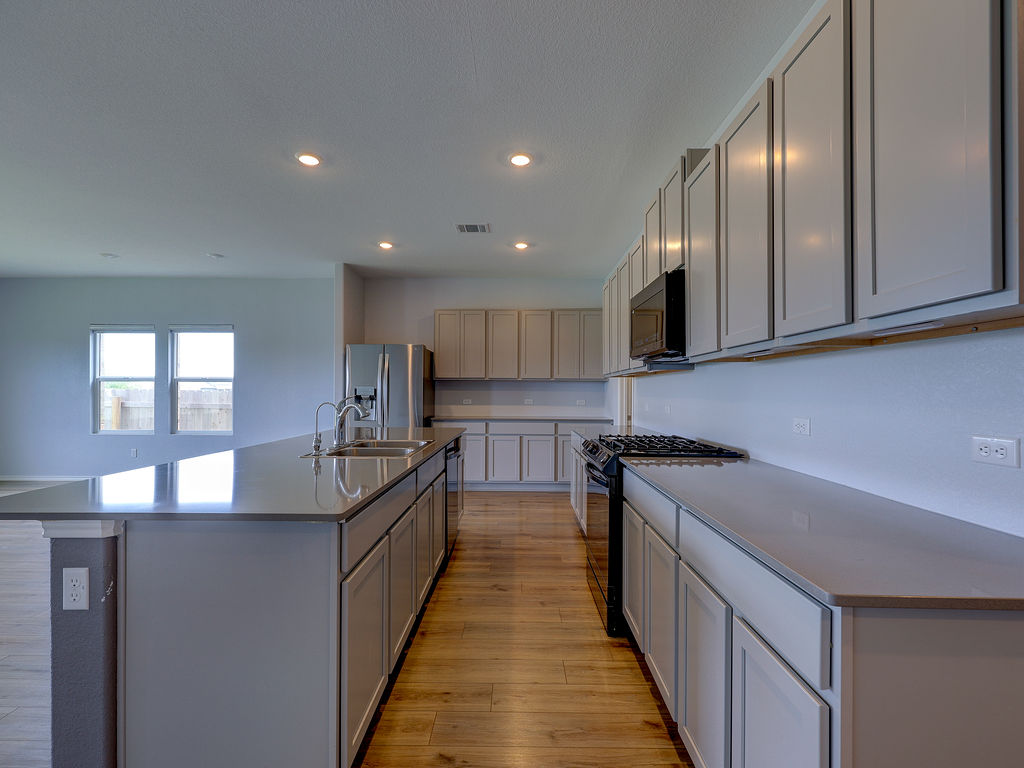 1716 Frontenac Street Leander, TX 78641 - Photo 8 of 34 a kitchen with stainless steel appliances granite countertop a sink a stove and a wooden floors