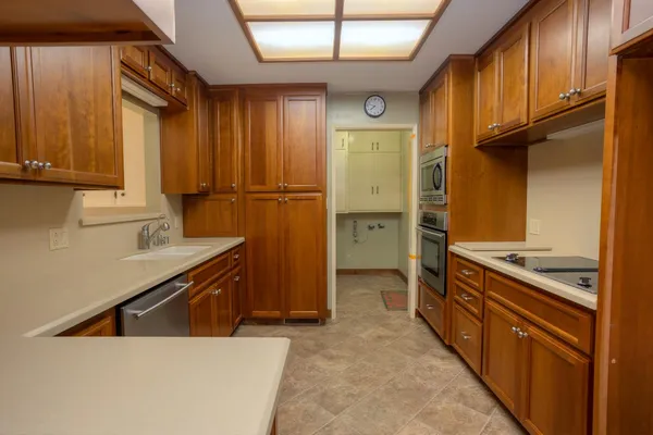 a kitchen with stainless steel appliances granite countertop a refrigerator a sink and wooden cabinets