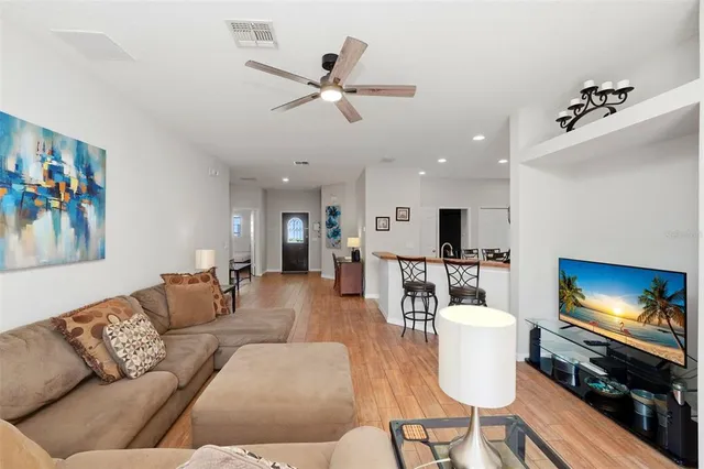 a living room with furniture a flat screen tv and kitchen view