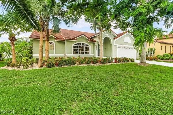 a front view of a house with a garden and trees