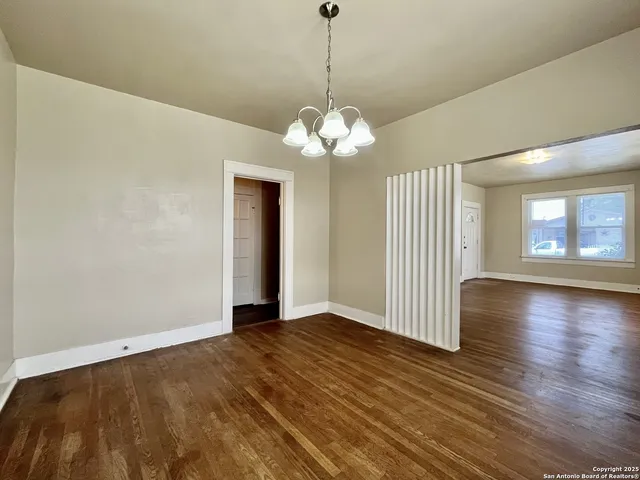 a view of a room with wooden floor chandelier and windows