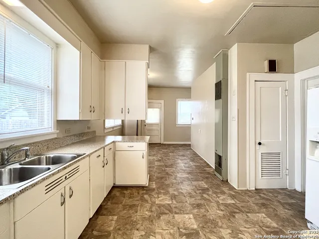 a large white kitchen with a sink and cabinets