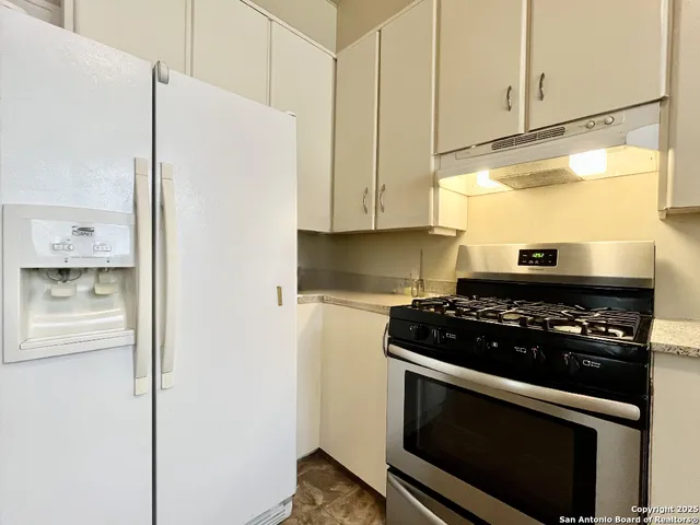 a kitchen with stainless steel appliances granite countertop white cabinets and a stove