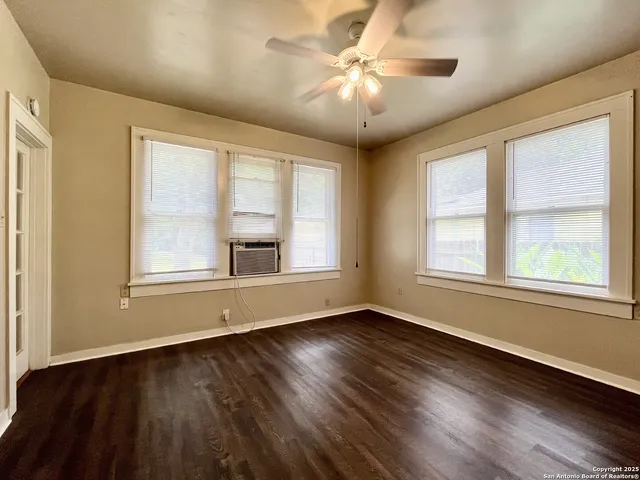 a view of an empty room with wooden floor and a window