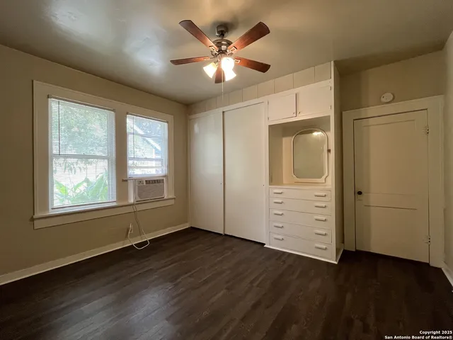 an empty room with wooden floor chandelier and windows
