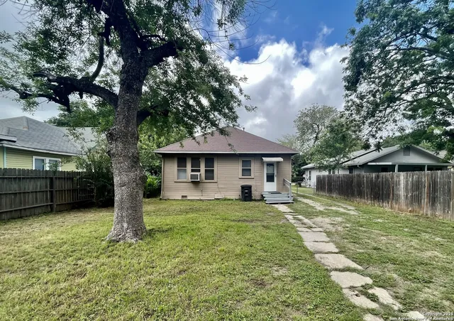 a view of a house with a yard and large tree