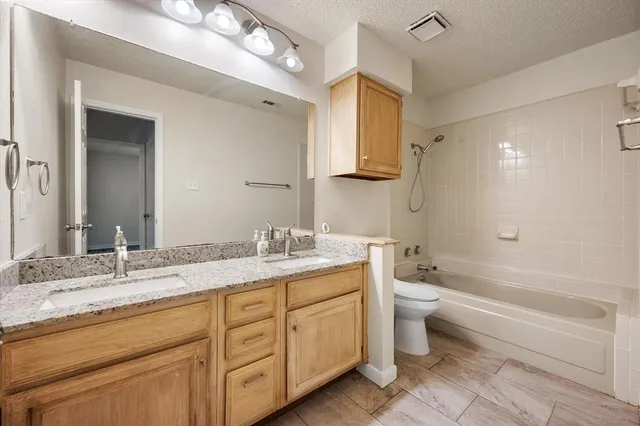 a bathroom with a granite countertop double vanity sink a mirror and a bathtub