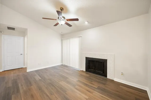 an empty room with wooden floor fireplace and windows