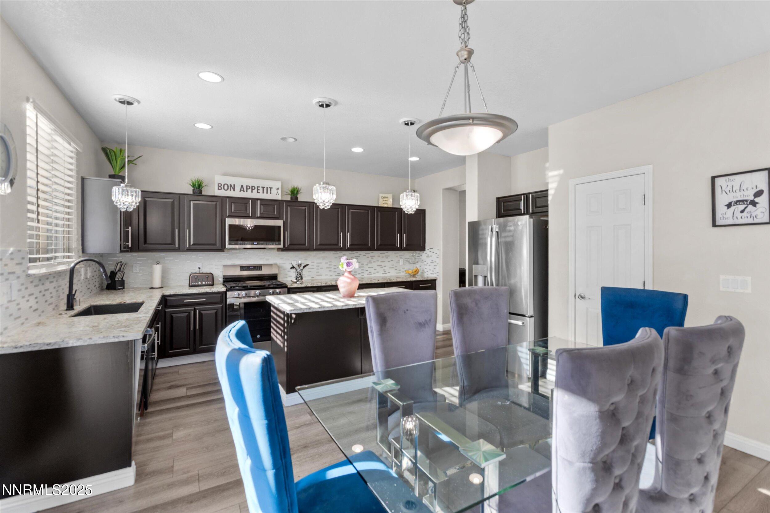 8922 Sorcha Street Reno, NV 89506 - Photo 14 of 47 a kitchen with stainless steel appliances granite countertop a refrigerator a stove top oven a sink dishwasher a dining table and chairs with wooden floor