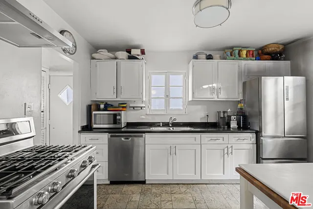 a kitchen with granite countertop a sink cabinets stainless steel appliances and a counter space