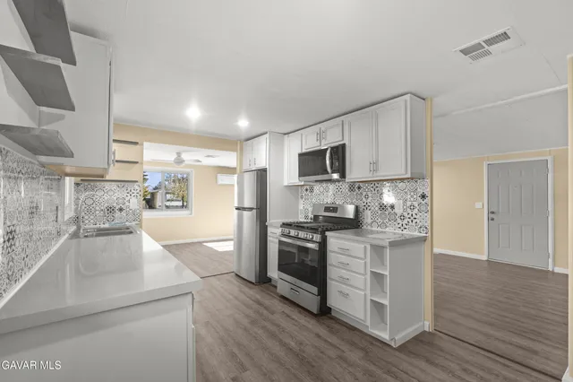 a kitchen with stainless steel appliances granite countertop a stove a sink and a refrigerator