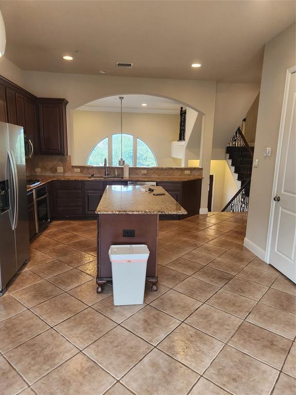 5720 Robbie Road Plano, TX 75024 - Photo 10 of 30 Kitchen featuring dark wood cabinetry, stainless steel refrigerator, granite countertops, and tile flooring