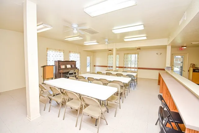 a dining hall with stainless steel appliances kitchen island granite countertop a table and chairs