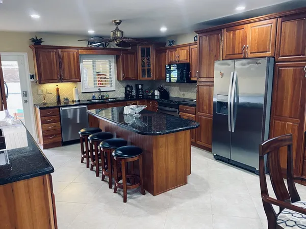 a kitchen with stainless steel appliances granite countertop a refrigerator a stove and a sink