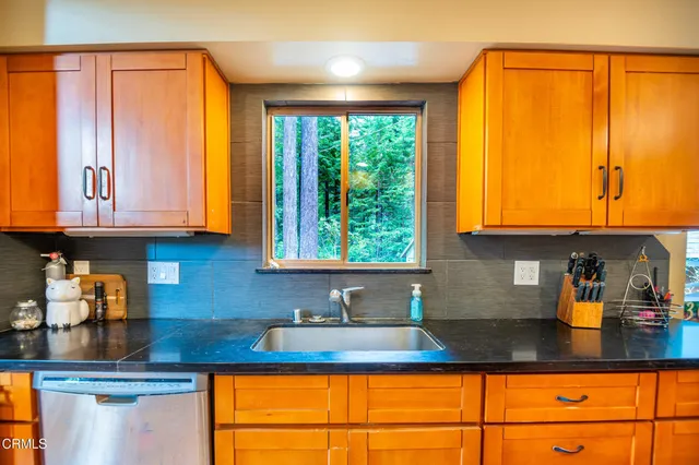 a kitchen with kitchen island granite countertop a sink a window and cabinets