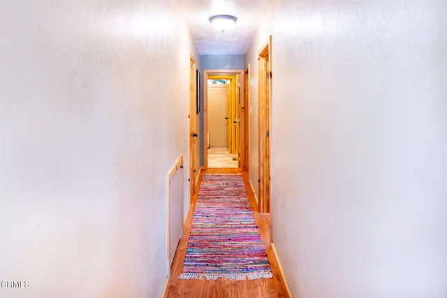 a view of a hallway with wooden floor and a bathroom