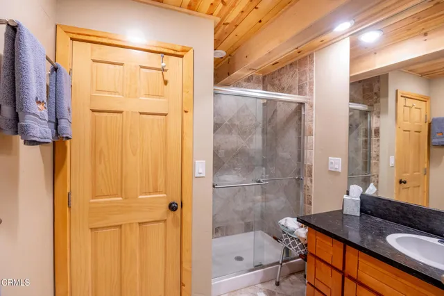 a bathroom with a granite countertop sink a mirror and shower