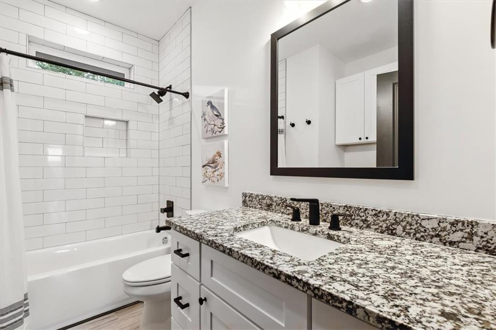 1379 Foxhound Trail Northeast Ranger, GA 30734 - Photo 22 of 42 a bathroom with a granite countertop sink a toilet a mirror a bathtub and shower