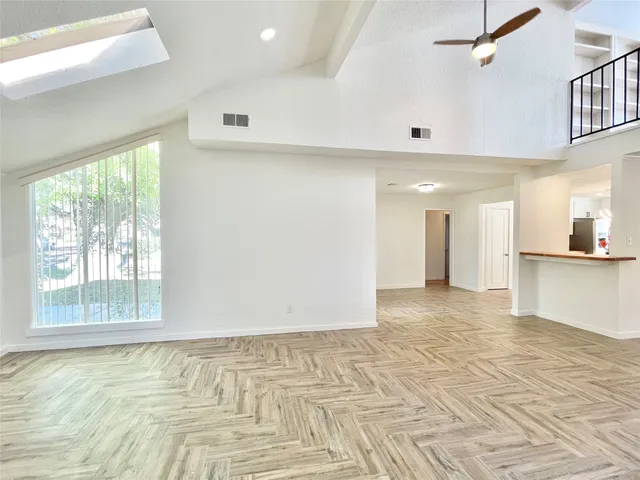 a view of an empty room with window and wooden floor