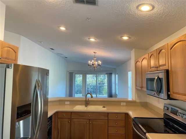 a kitchen with granite countertop a refrigerator stove and sink
